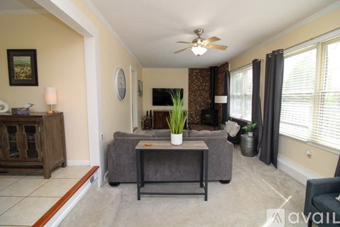 A living room with a grey couch and a ceiling fan.