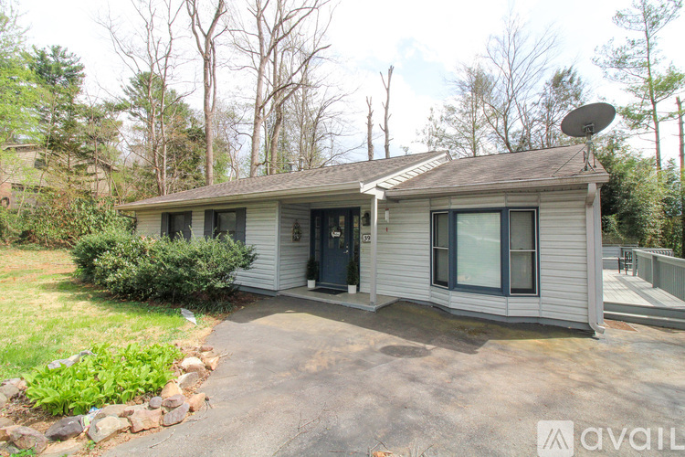 A house with a grey roof and a black door is surrounded by trees.