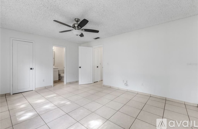 A spacious room with a ceiling fan and tiled flooring.