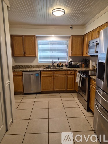 A kitchen with wooden cabinets and a stainless steel refrigerator.