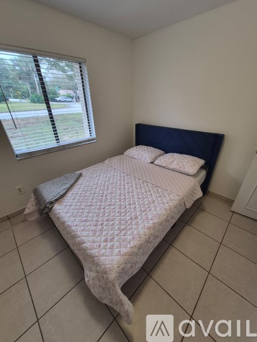 A bedroom with a bed, pillows, and a window with blinds.