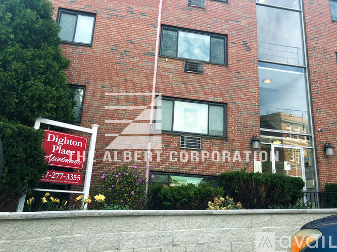 A red brick building with a sign that says "Albert Corporation" in front of it.