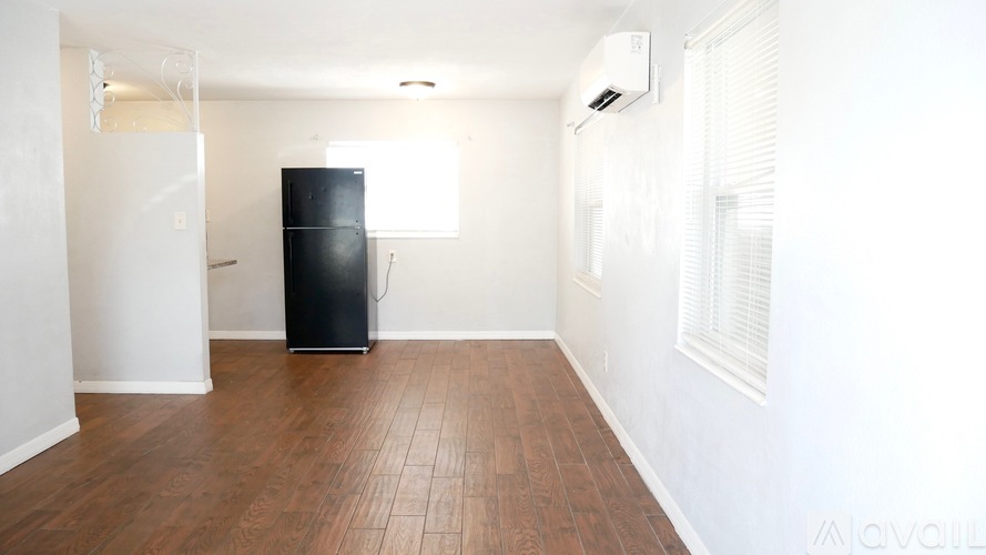 A black fridge in a room with wooden floors and white walls.