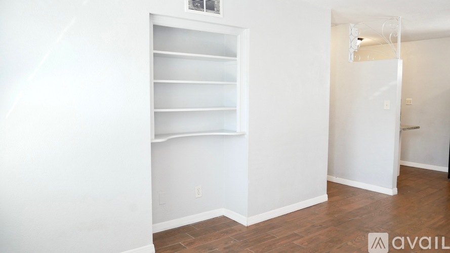 A white wall with a shelf and a door.