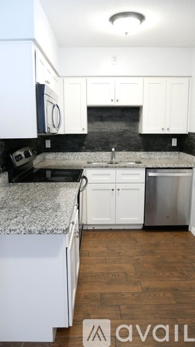 A kitchen with white cabinets and a granite countertop.