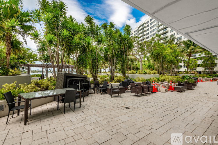 A patio with a table and chairs is surrounded by trees.