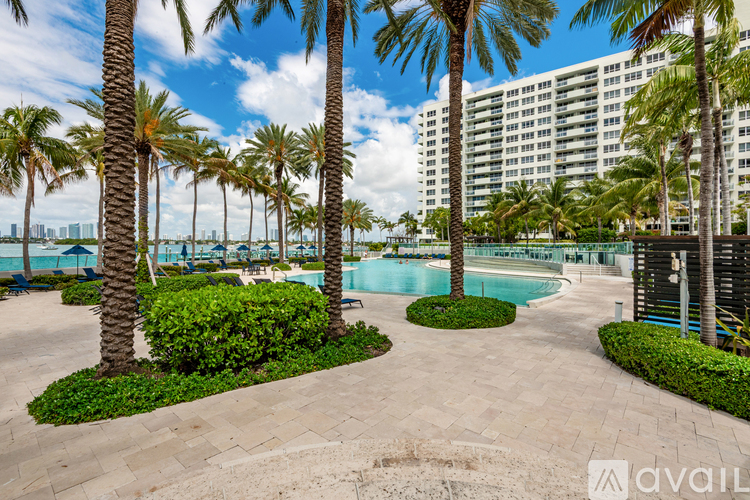 A pool surrounded by palm trees and bushes.