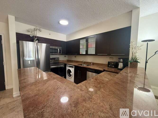 A kitchen with dark brown granite countertops and black cabinets.