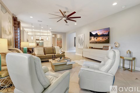 A living room with a white ceiling fan and a large painting on the wall.