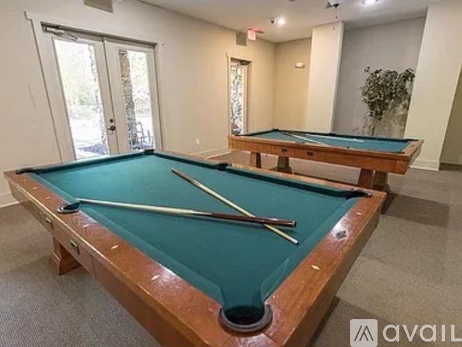 A pool table with a green felt cloth and a white cue stick.