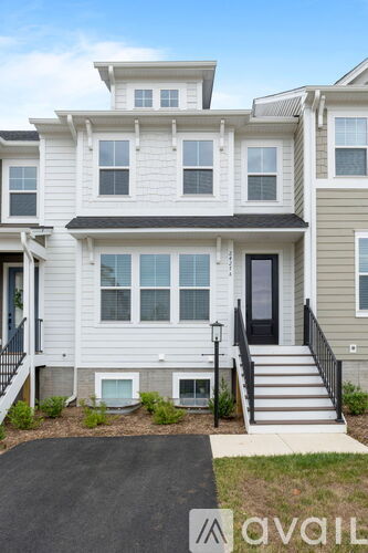 A two-story house with a front yard and a black gate.
