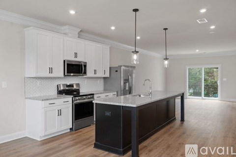 A kitchen with white cabinets and a black island.