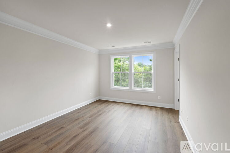 A room with wooden flooring and a window with a view of trees.
