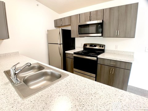 A kitchen with a sink, stove, and refrigerator.