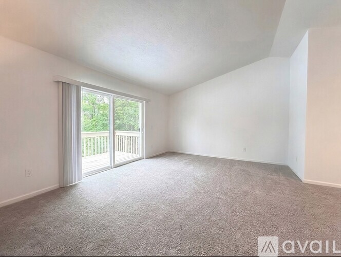 A room with a carpeted floor and a sliding glass door leading to a deck.