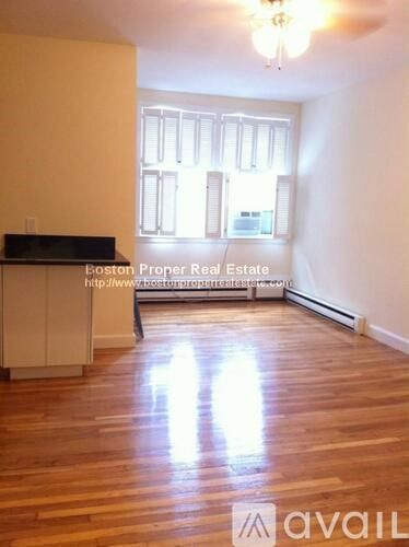 A room with wooden floors and a window with blinds.