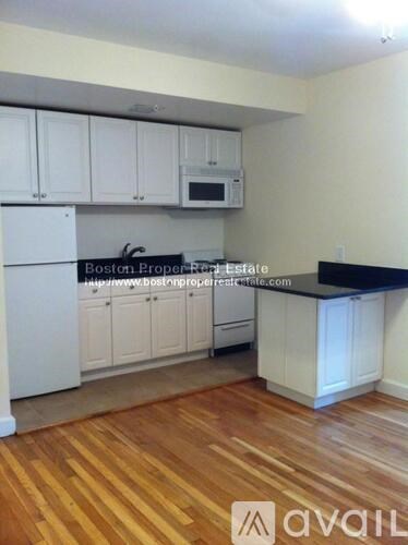 A kitchen with white cabinets and a wooden floor.