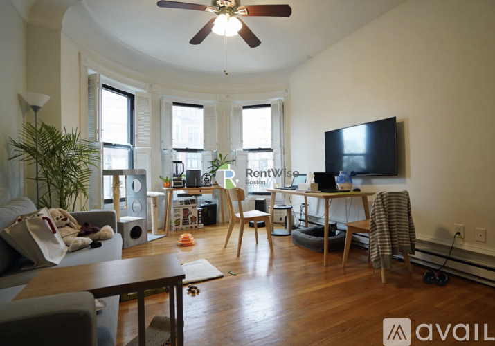 A living room with a television, a couch, a coffee table, and a potted plant.