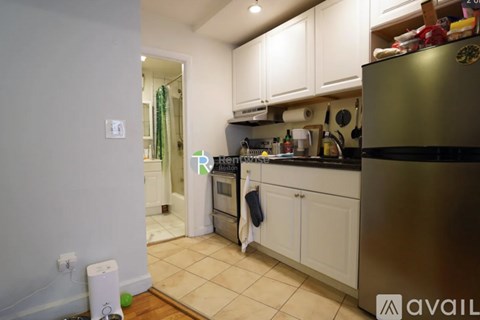 A kitchen with white cabinets and a black fridge.