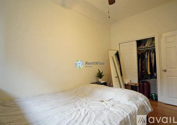 A bedroom with a bed, a wardrobe, and a logo on the wall.