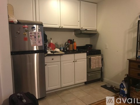 A kitchen with white cabinets and a stainless steel refrigerator.