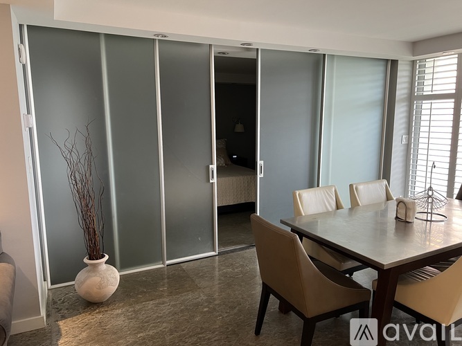 A dining room with a table and chairs and a glass door.