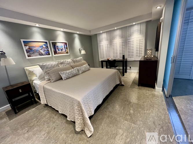 A bedroom with a large bed and a painting on the wall.