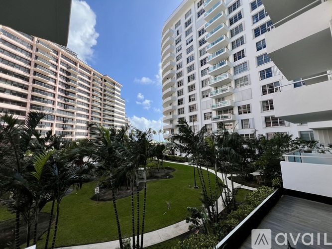 A modern building with a balcony overlooking a green lawn.