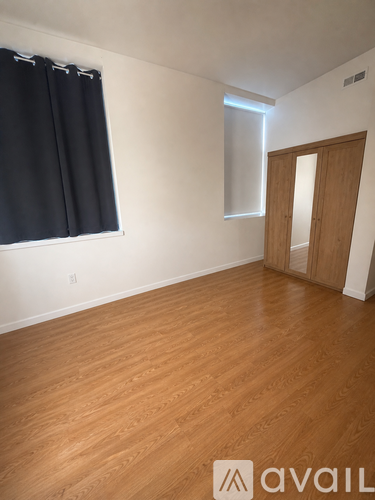 A room with wooden flooring and a door on the right side.