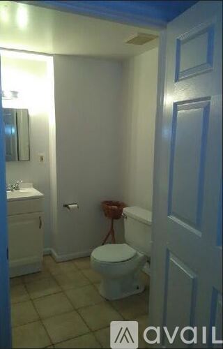 A white toilet in a small bathroom with a white sink and a white door.