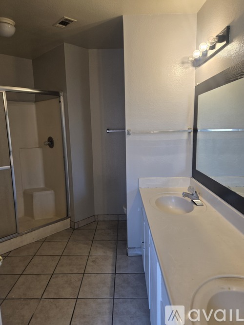 A bathroom with a sink, mirror, and shower.