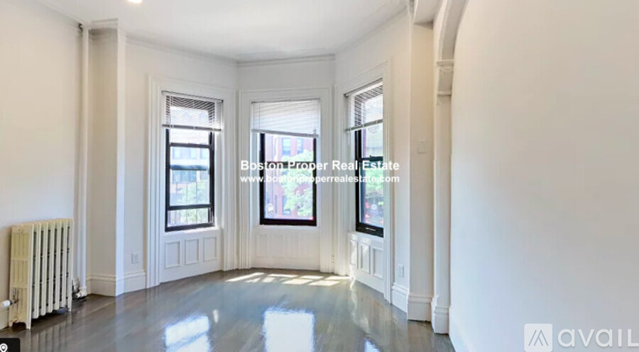 A spacious room with white walls and a radiator on the left side.