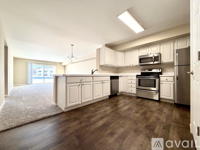 A kitchen with white cabinets and a wooden floor.