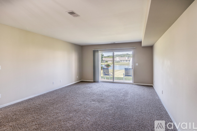 A spacious room with a carpeted floor and sliding glass doors leading to a balcony.