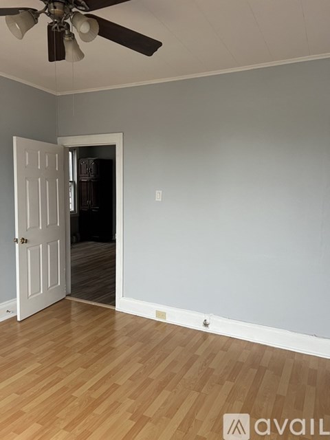 A room with a white door and a ceiling fan.