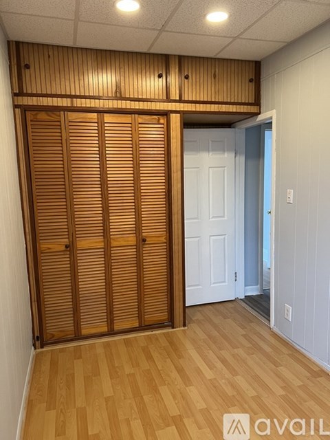 Closed wooden doors in a room with a white door and wall.