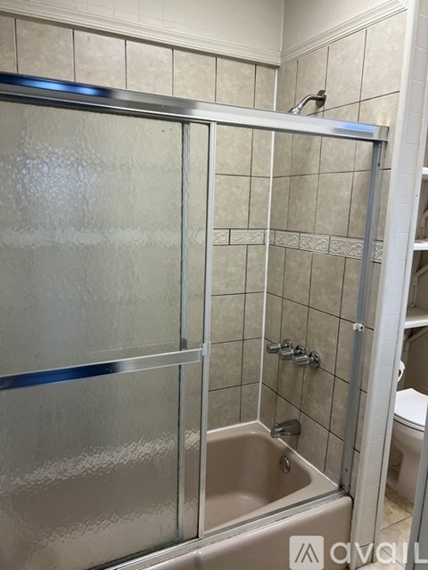 A shower stall with a glass door and a white tiled wall.