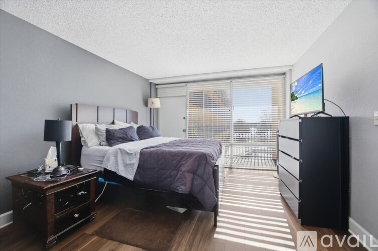 A bedroom with a bed, nightstand, and a television.