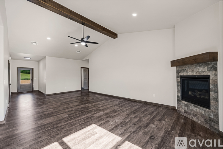 A spacious living room with a fireplace and a rug on the floor.