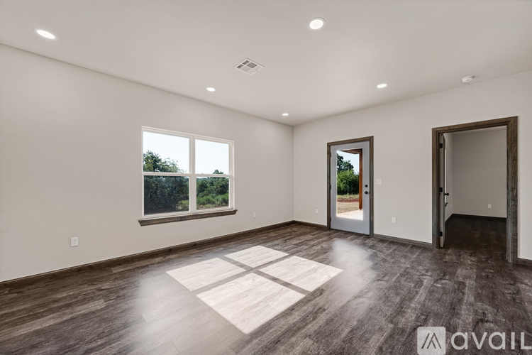 A spacious room with wooden floors and a large window.