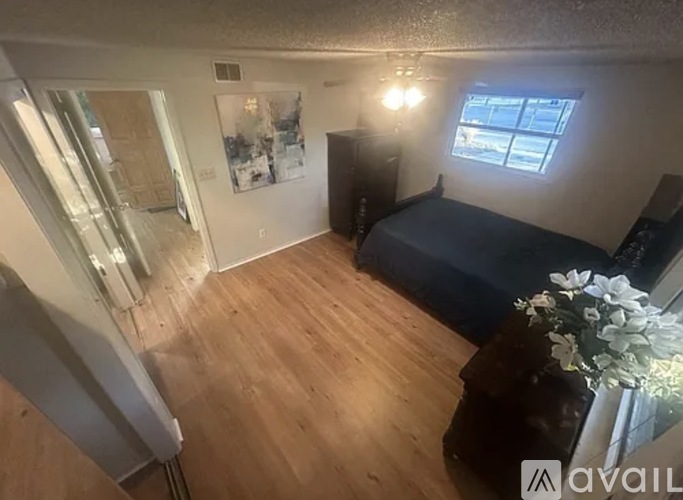 A bedroom with a bed, dresser, and window.