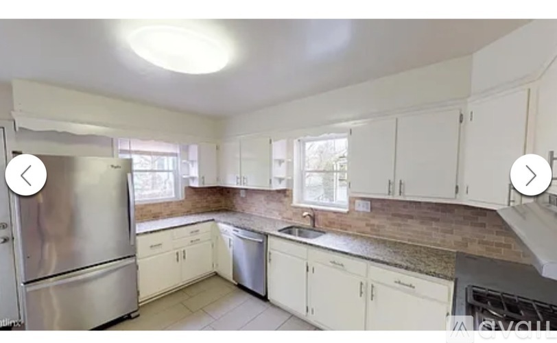 A kitchen with white cabinets and a stainless steel refrigerator.