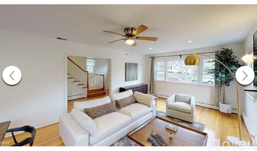 A living room with a white couch and a ceiling fan.