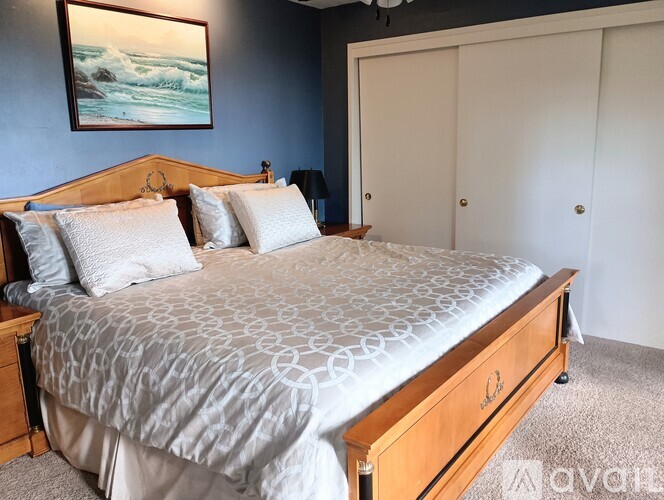 A bedroom with a large bed and a painting on the wall.