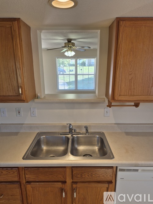 A kitchen with wooden cabinets and a double sink.