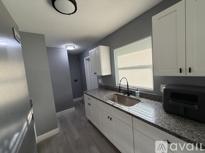 A kitchen with white cabinets and a granite countertop.
