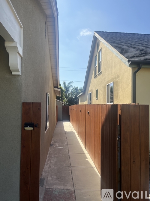 A narrow alley with wooden fences and houses on either side.