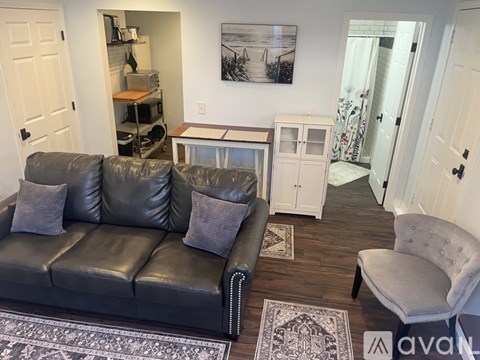 A black leather couch with grey cushions is in the living room.
