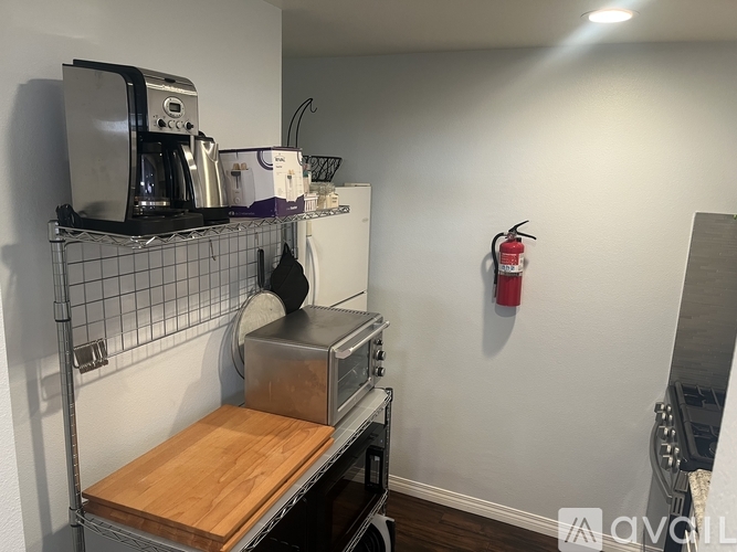 A kitchen area with a coffee maker, a pot, and a wooden cutting board.