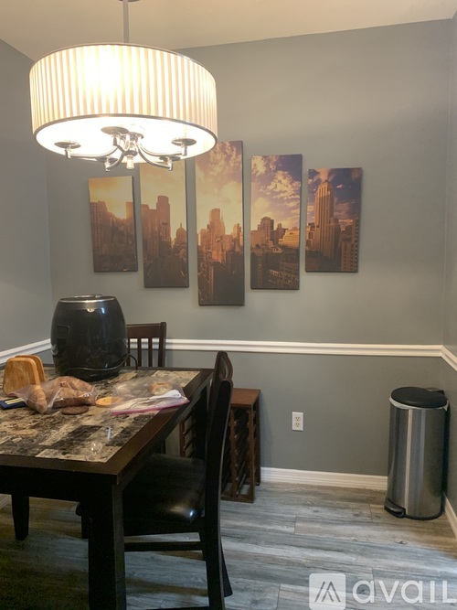 A dining room with a table, chairs, and a large painting on the wall.